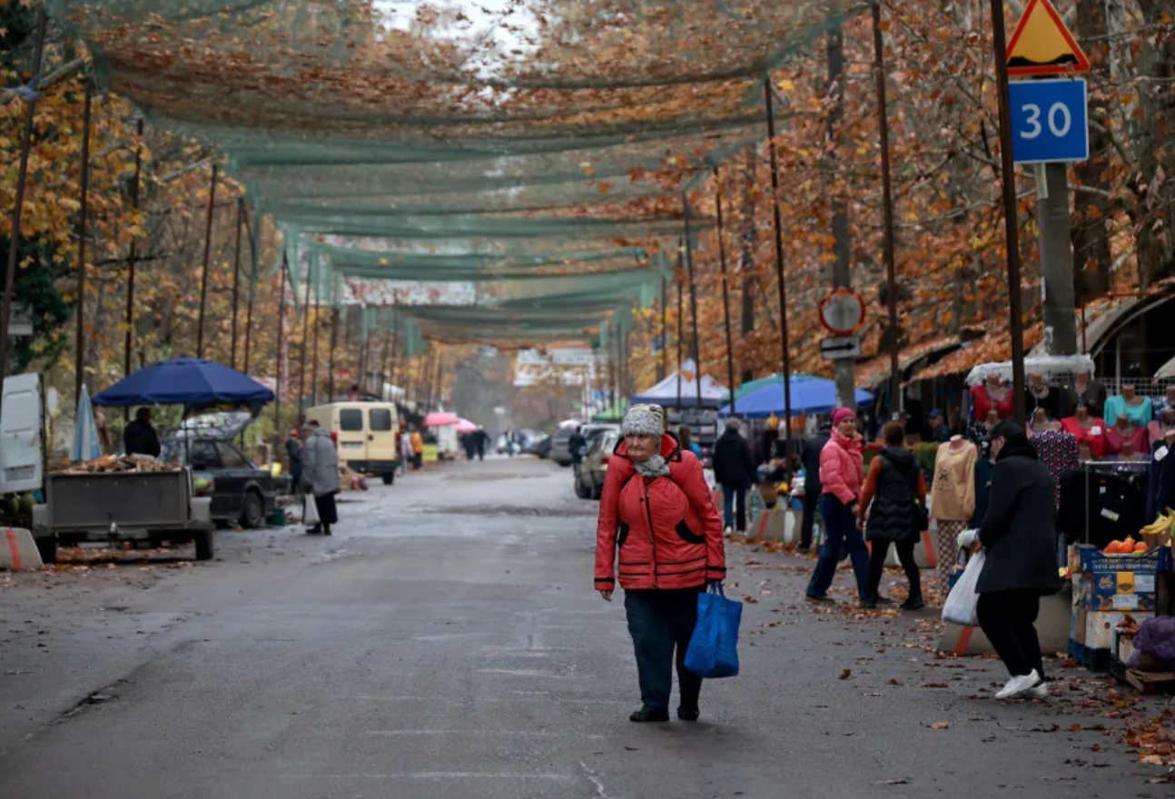 Люди відвідують вуличний ринок, перегородженій сітками проти дронів для захисту від російських безпілотників у Херсоні, 11 листопада 2025 року